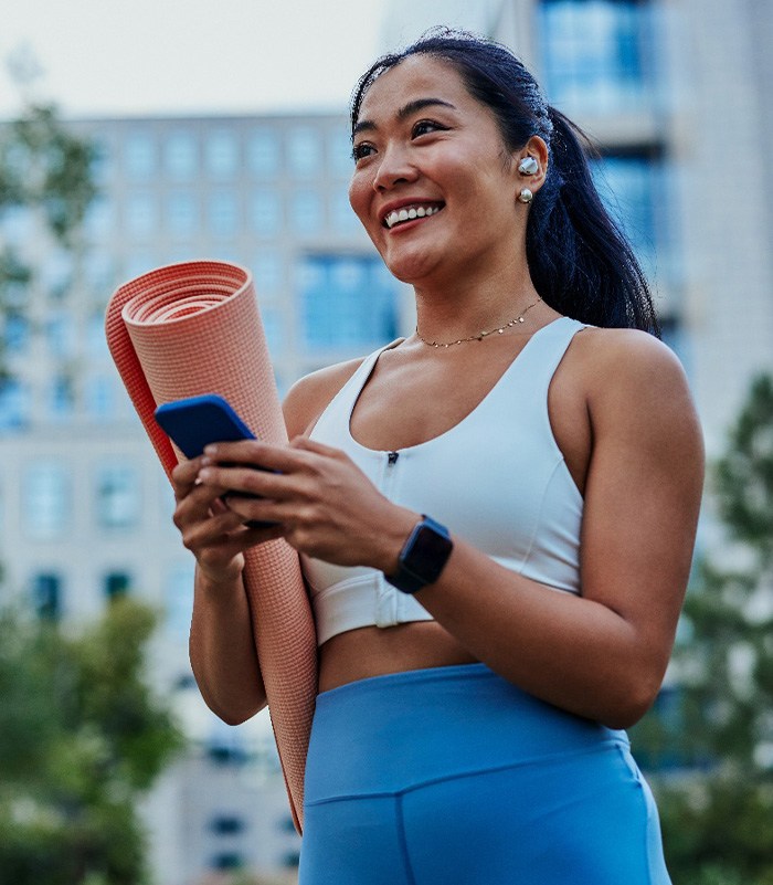 Smiling woman walking on park with workout mat