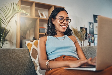 Smiling woman working on laptop on couch