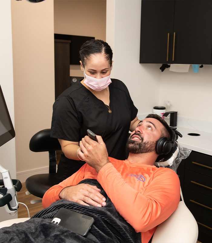 Dental patient with blanket and headphones receiving remote control from dental team member
