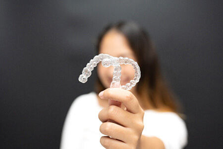 smiling patient holding clear aligner