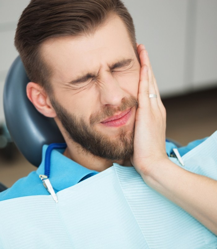 Man holding jaw in pain before emergency dentistry