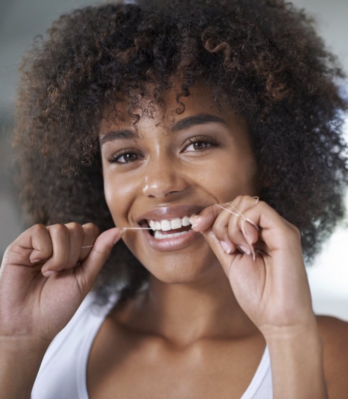 Woman flossing teeth to prevent dental emergencies