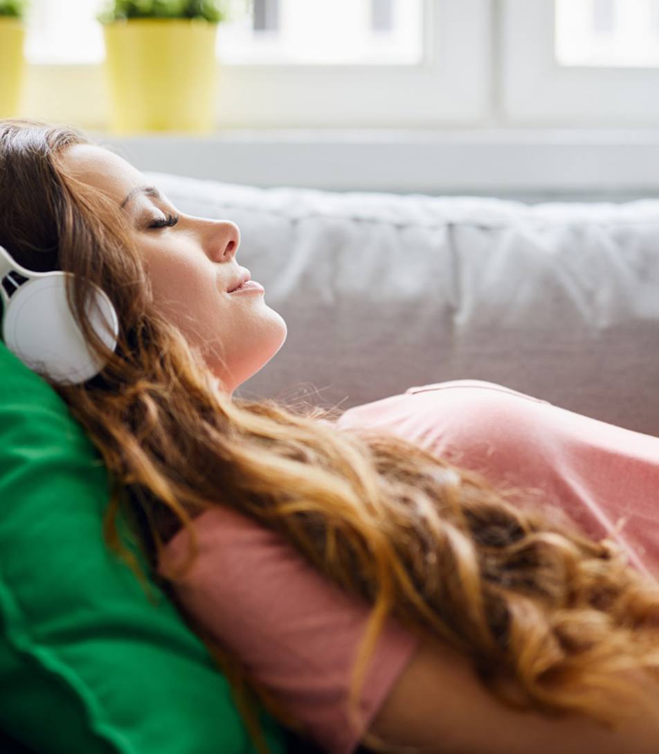 Woman relaxing on sofa wearing headphones