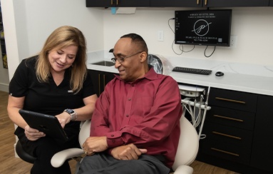 Dental team member and dentistry patient looking at chairside computer in Royal Palm Beach