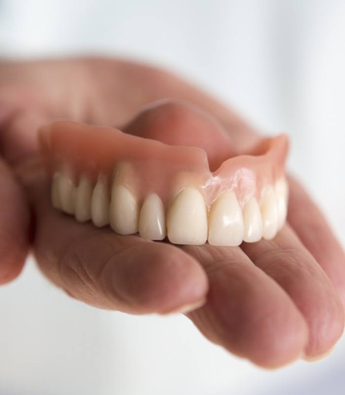 Hand holding a full denture