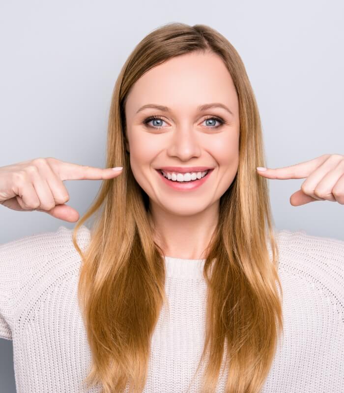 Woman pointing to smile after Invisalign treatment