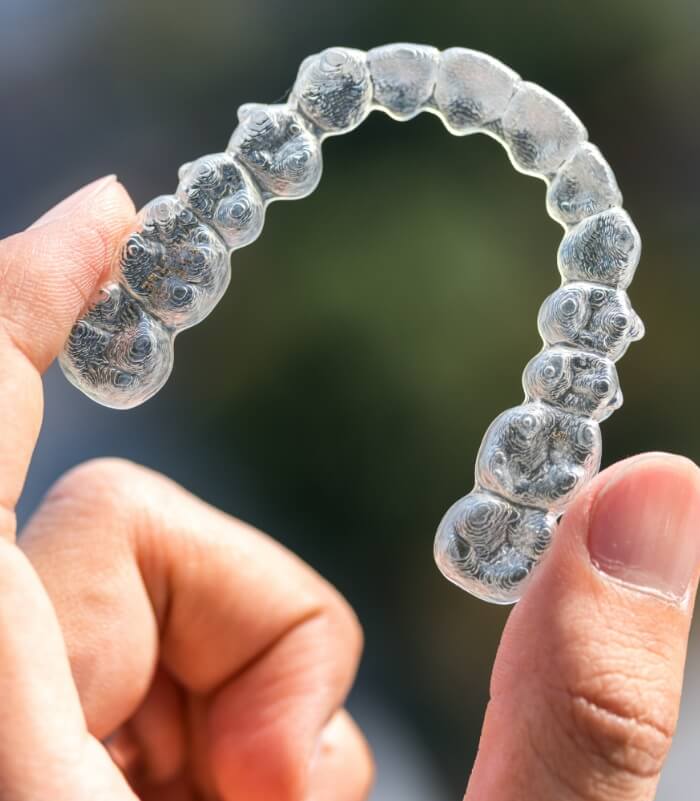 Hand holding an Invisalign aligner tray