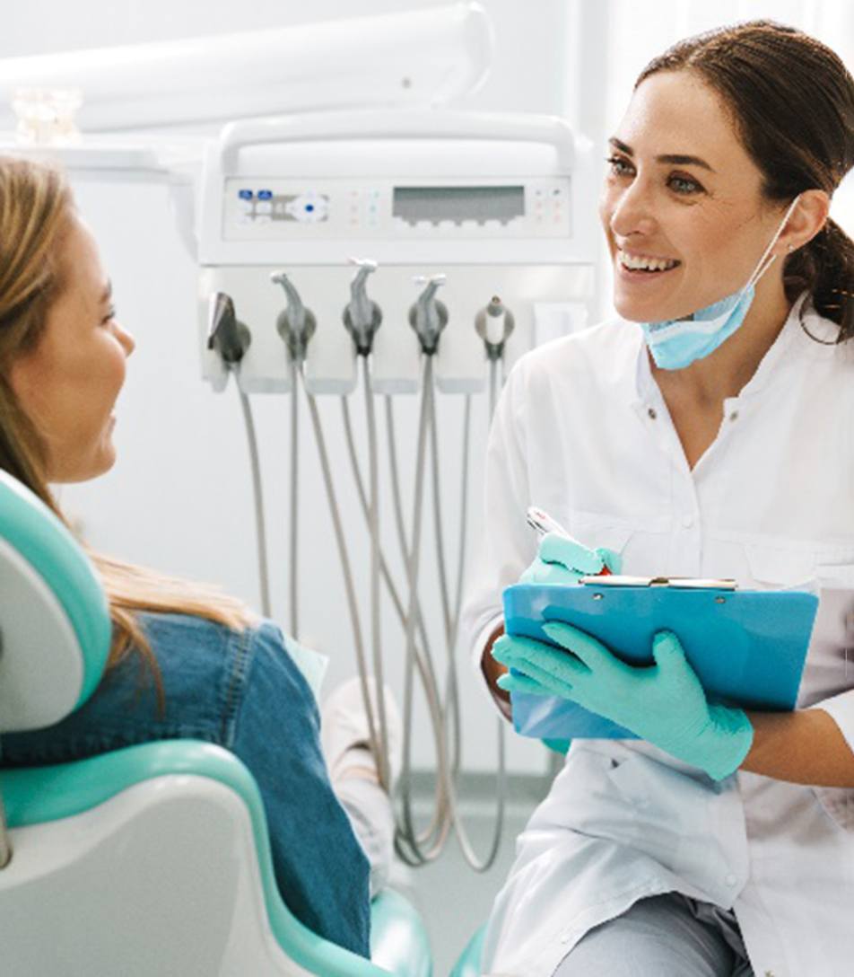 Cosmetic dentist smiling at patient while taking notes