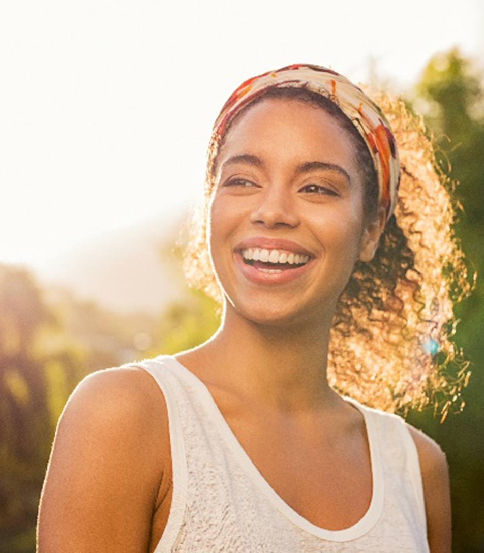Woman with veneers smiling while walking outside at sunset