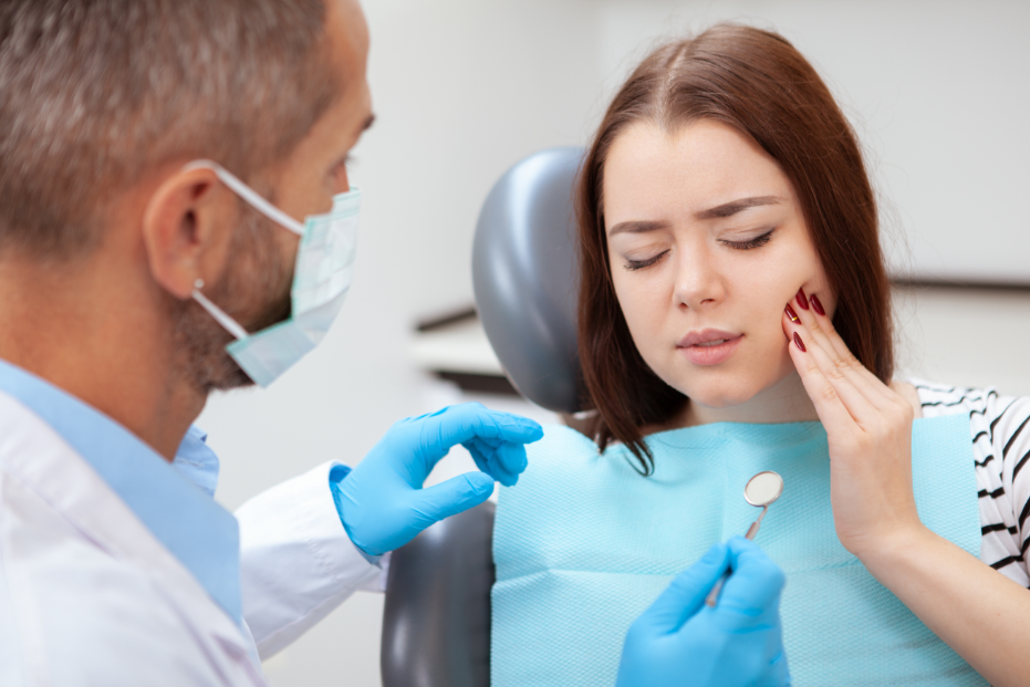 Woman holding jaw in pain, at dentist
